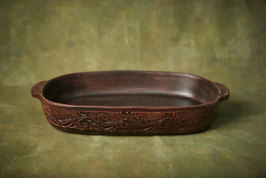 Handmade dark brown clay serving dish with embossed floral scroll patterns.