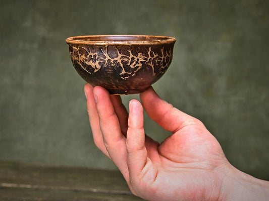 Handmade clay bowl with rustic crackle glaze, held in hand for artisan home decor