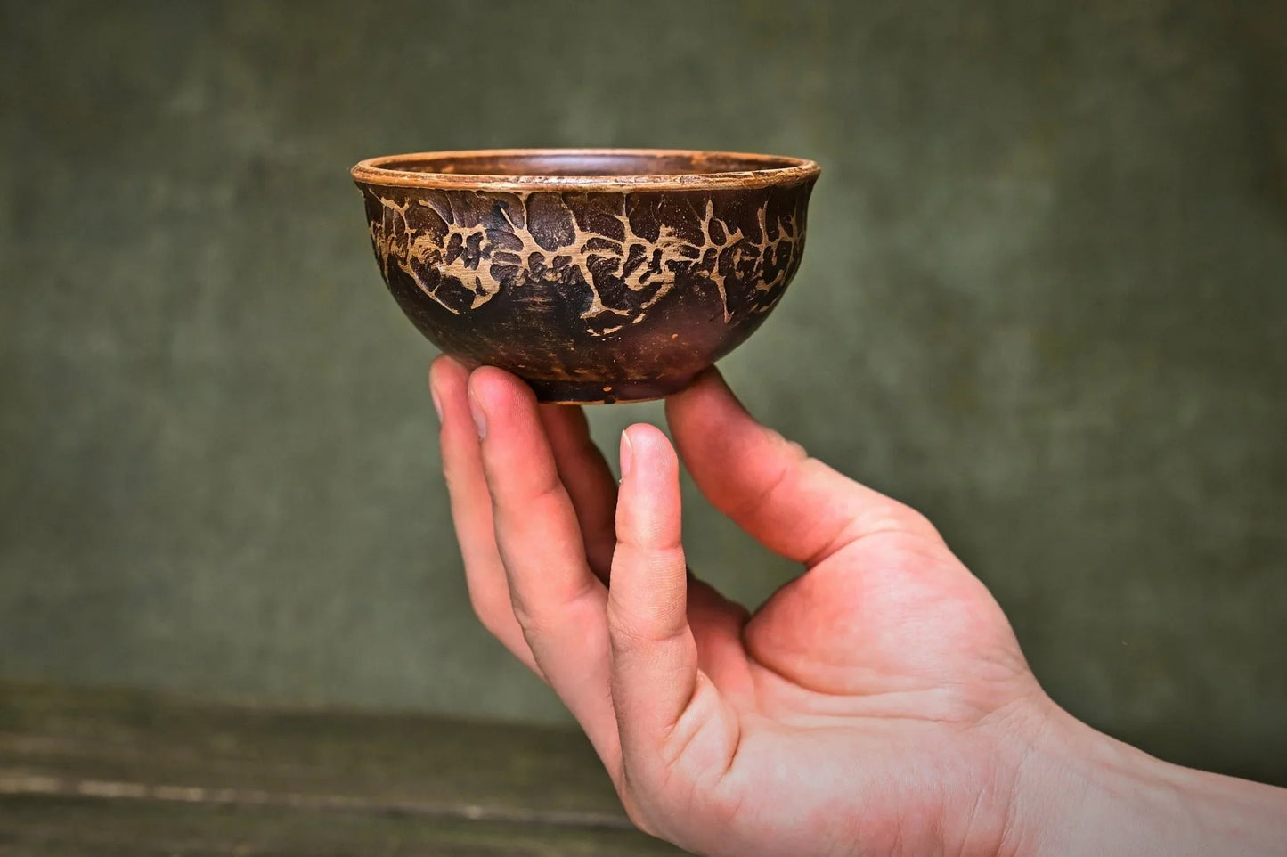Hand holding artisan handmade clay bowl with rustic crackle glaze, perfect for home decor and sustainable living.