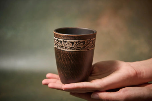 Hand holding artisan handmade clay mug with carved leaf pattern, rustic ceramic homeware for cozy décor