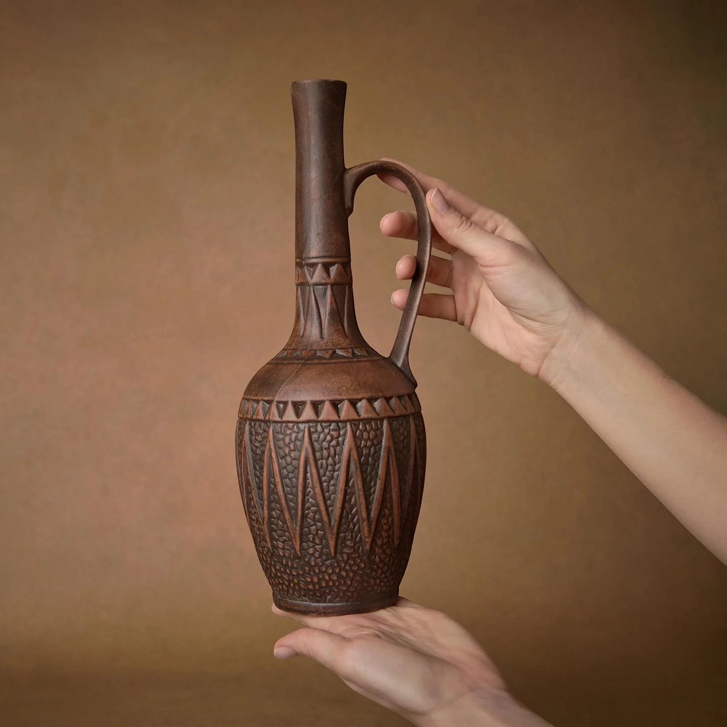 Handcrafted clay pitcher with geometric patterns, perfect for rustic home decor