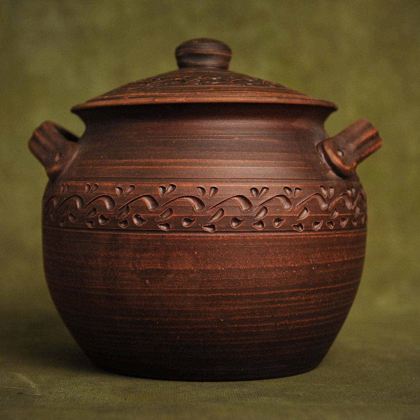 Handcrafted clay pot with carved floral design, perfect for rustic home decor