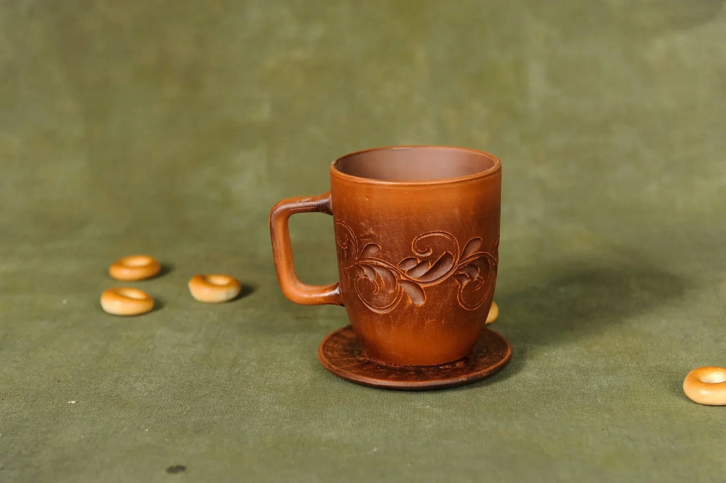 Handmade ceramic cup with plate, clay pottery mug for tea or coffee on green background