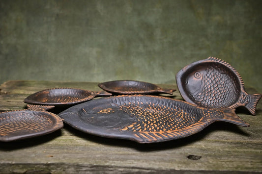 Handcrafted clay fish-shaped ceramic plates set on rustic wood, artisan homeware