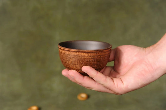 Hand holding a rustic handmade ceramic dipping bowl, brown pottery homeware from clayproductsshop