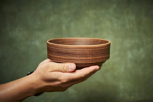 Hand holding a handmade ceramic clay bowl with intricate texture, artisan pottery homeware