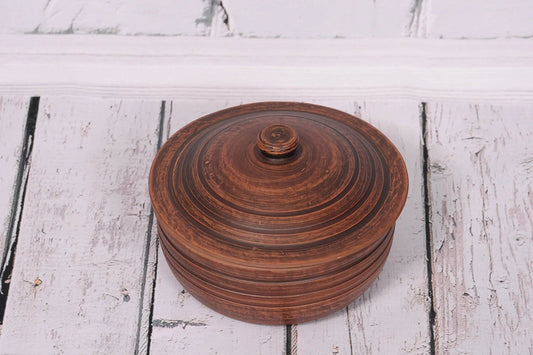 Handmade ceramic clay cooking pot with lid, rustic brown, on white wooden surface