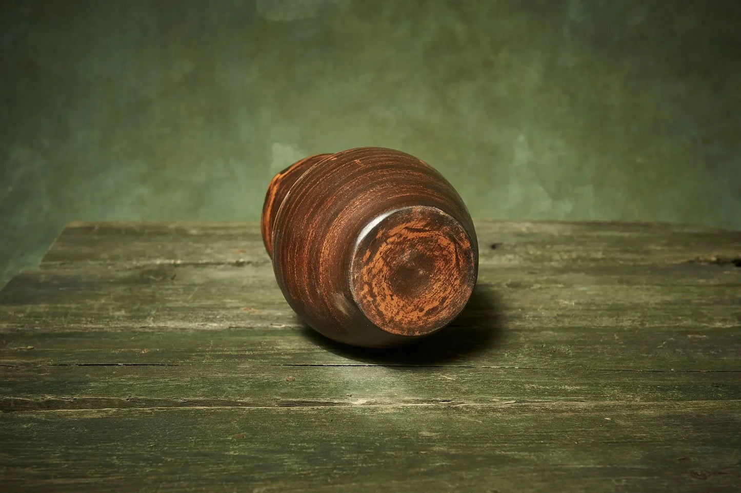Handmade brown ceramic pitcher on rustic wooden table, artisan clay homeware