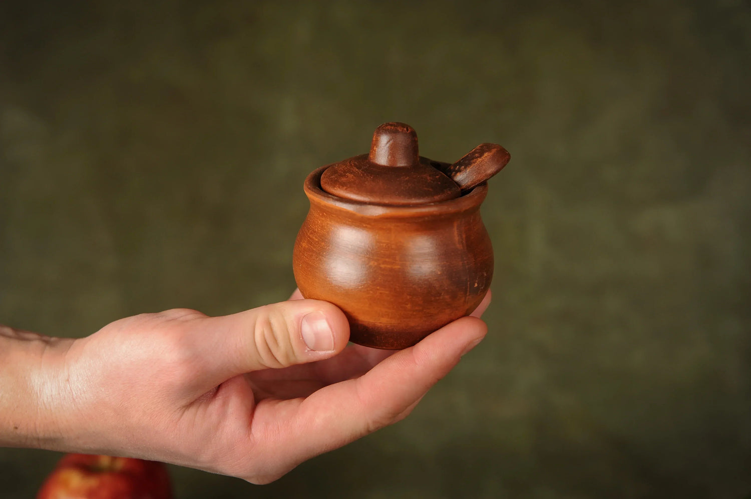 Hand holding a handmade brown clay salt and pepper shaker with lid and spoon, clayproductsshop homeware