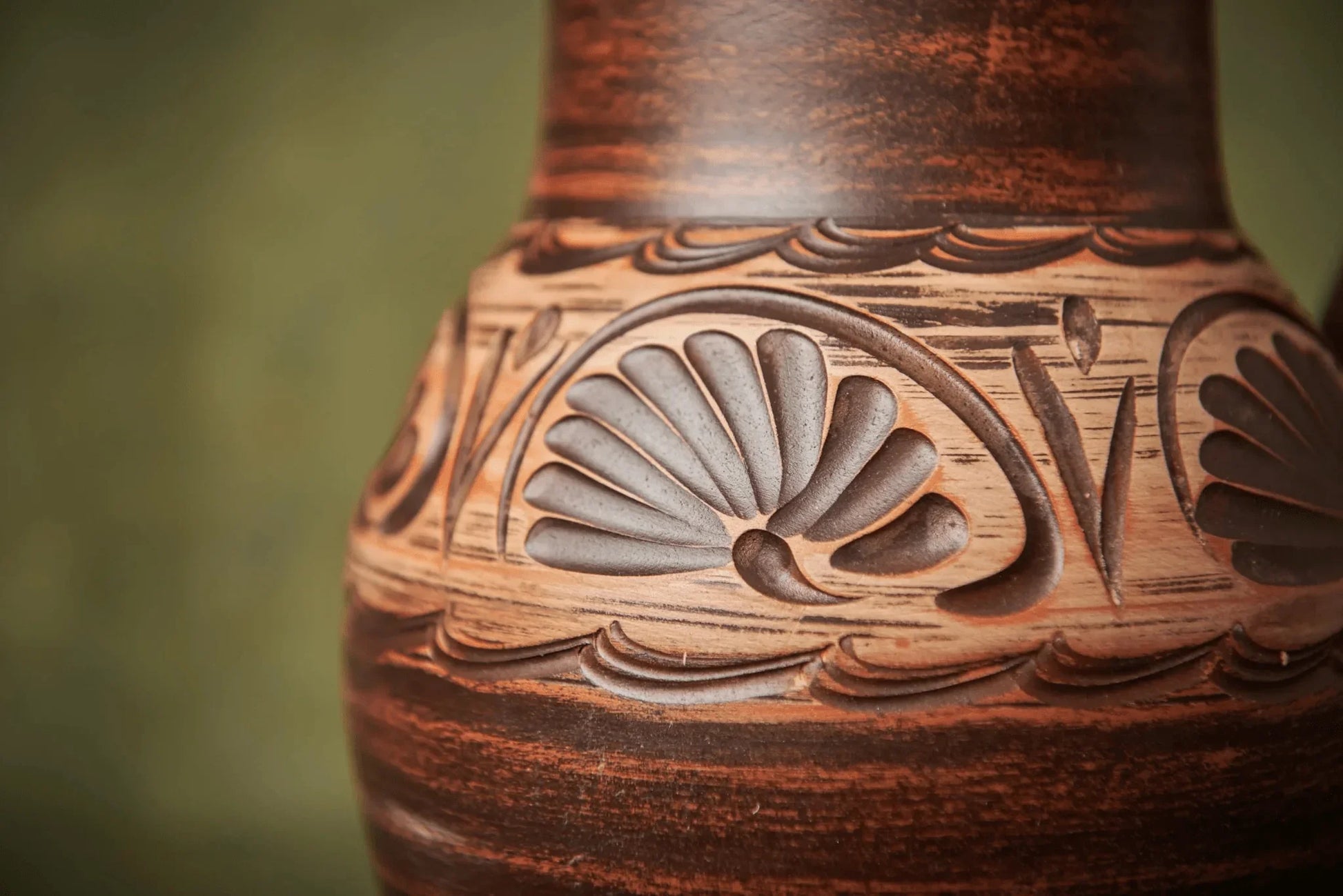 Close-up of carved handmade clay jug with textured floral patterns, artisan ceramic homeware