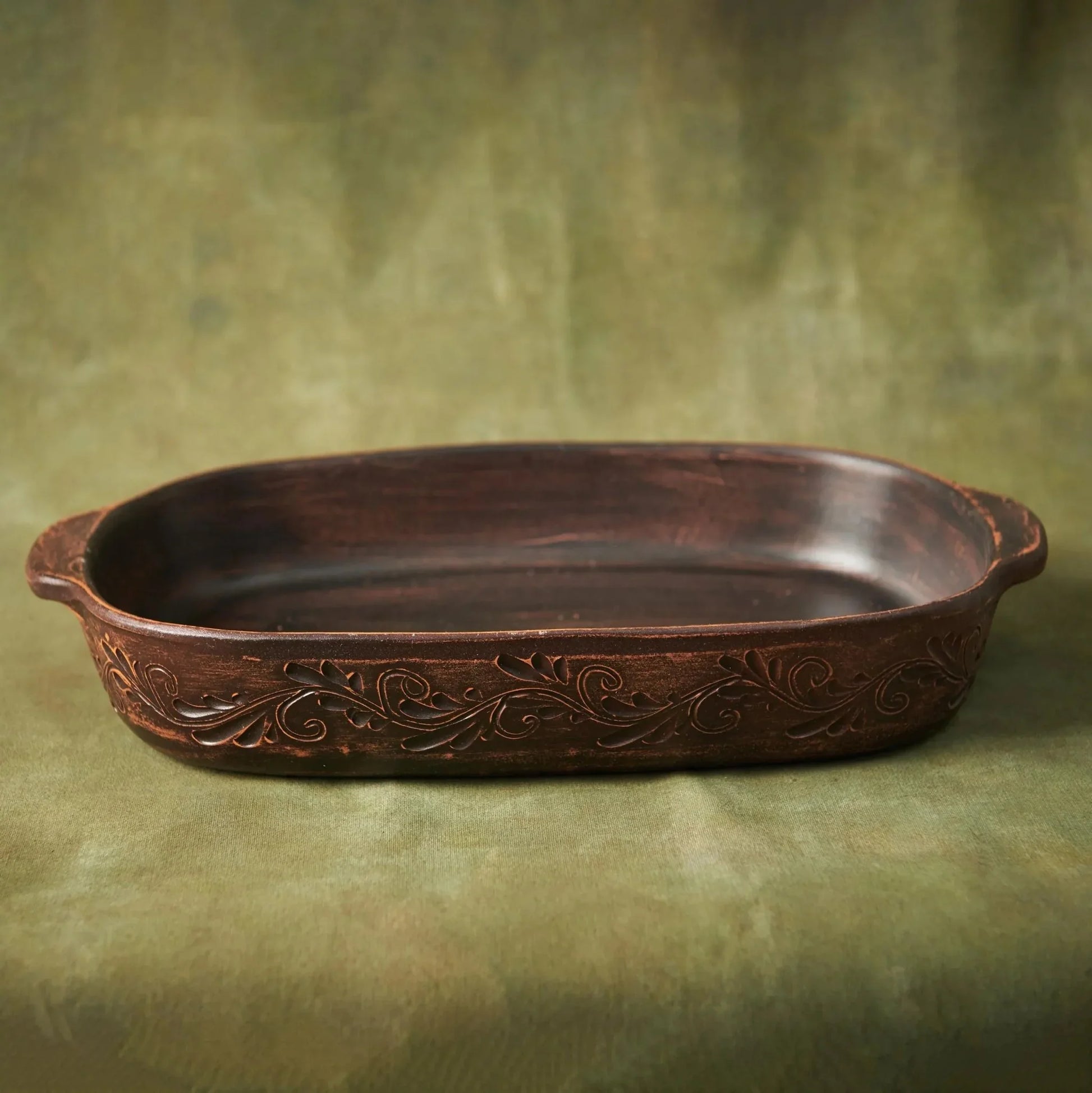 Handmade ceramic baking tray with floral pattern, artisan pottery lasagna pan on green backdrop