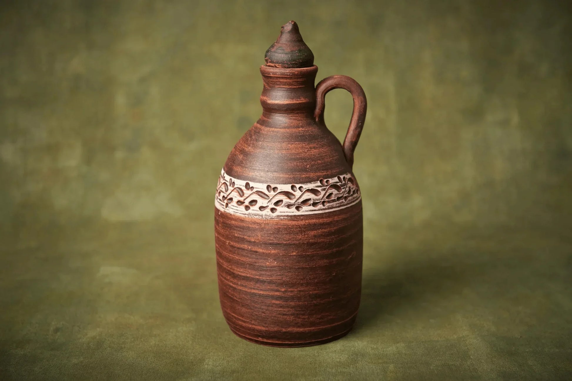 Handmade ceramic amphora-style clay bottle with lid and handle, brown with decorative band