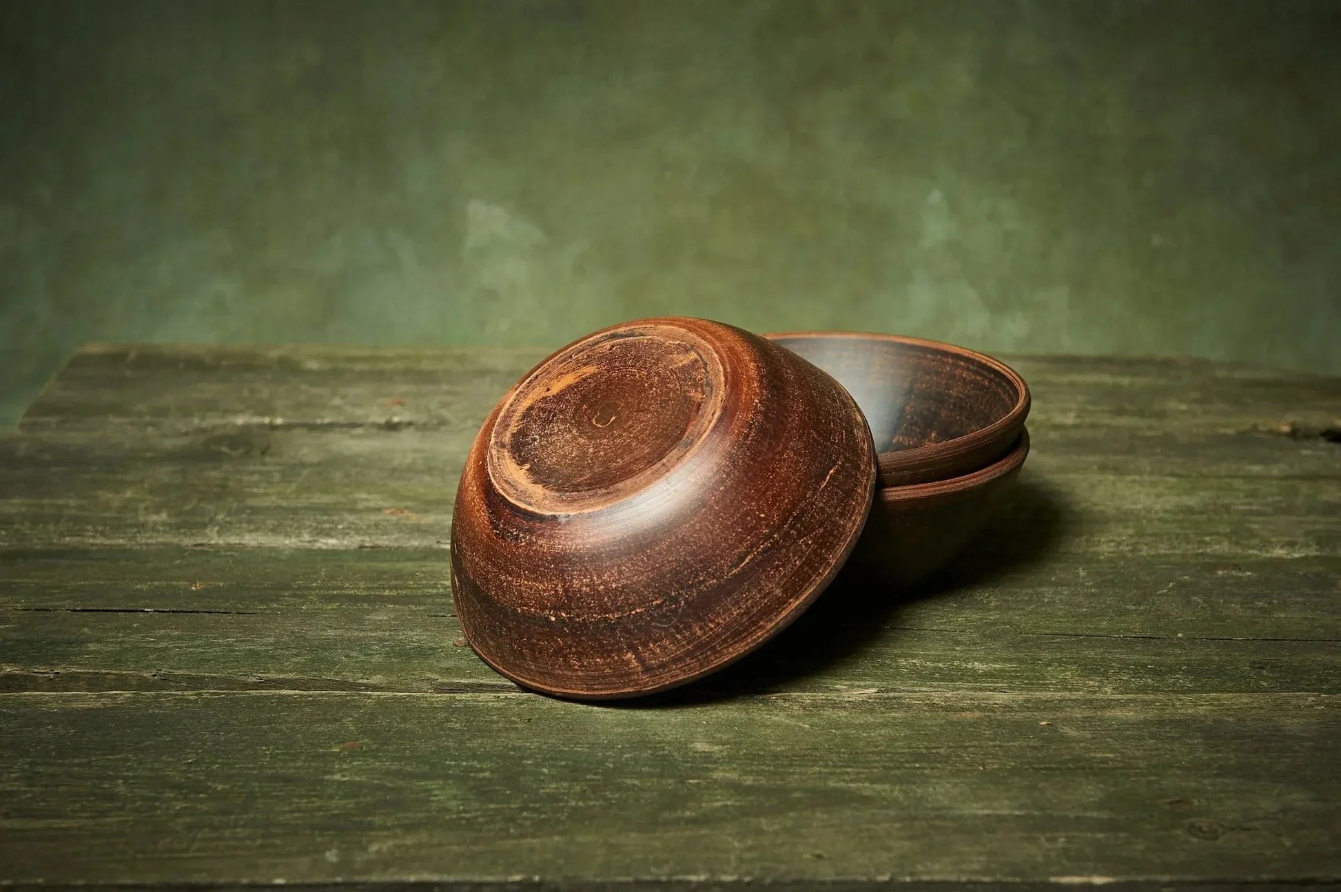 Handmade deep red clay ceramic bowls set of three on rustic wooden table, Ukrainian pottery