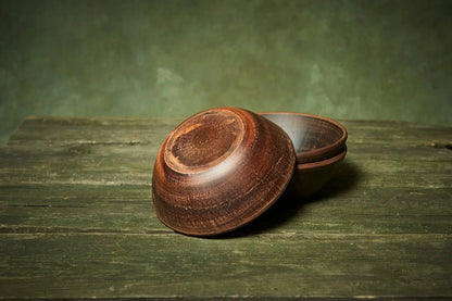 Handmade deep red clay ceramic bowls set of three on rustic wooden table, Ukrainian pottery