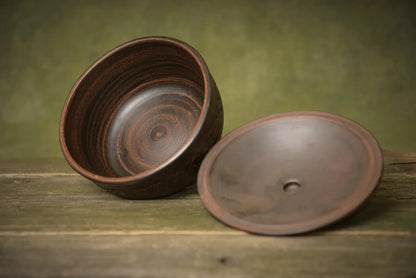 Handmade ceramic bread pot with matching lid on rustic wood, artisan clay bakeware