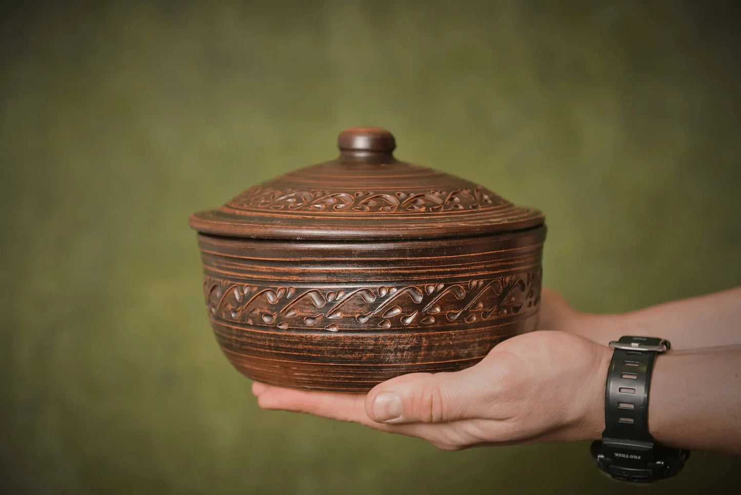 Hand holding a handmade ceramic bread pot baking dish with lid, artisan clay homeware