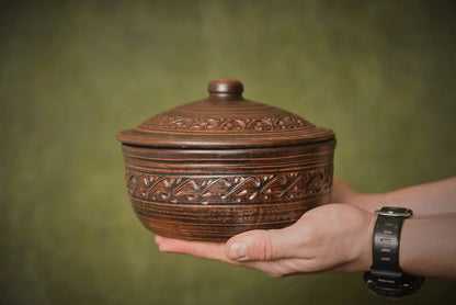 Hand holding a handmade ceramic bread pot baking dish with lid, artisan clay homeware