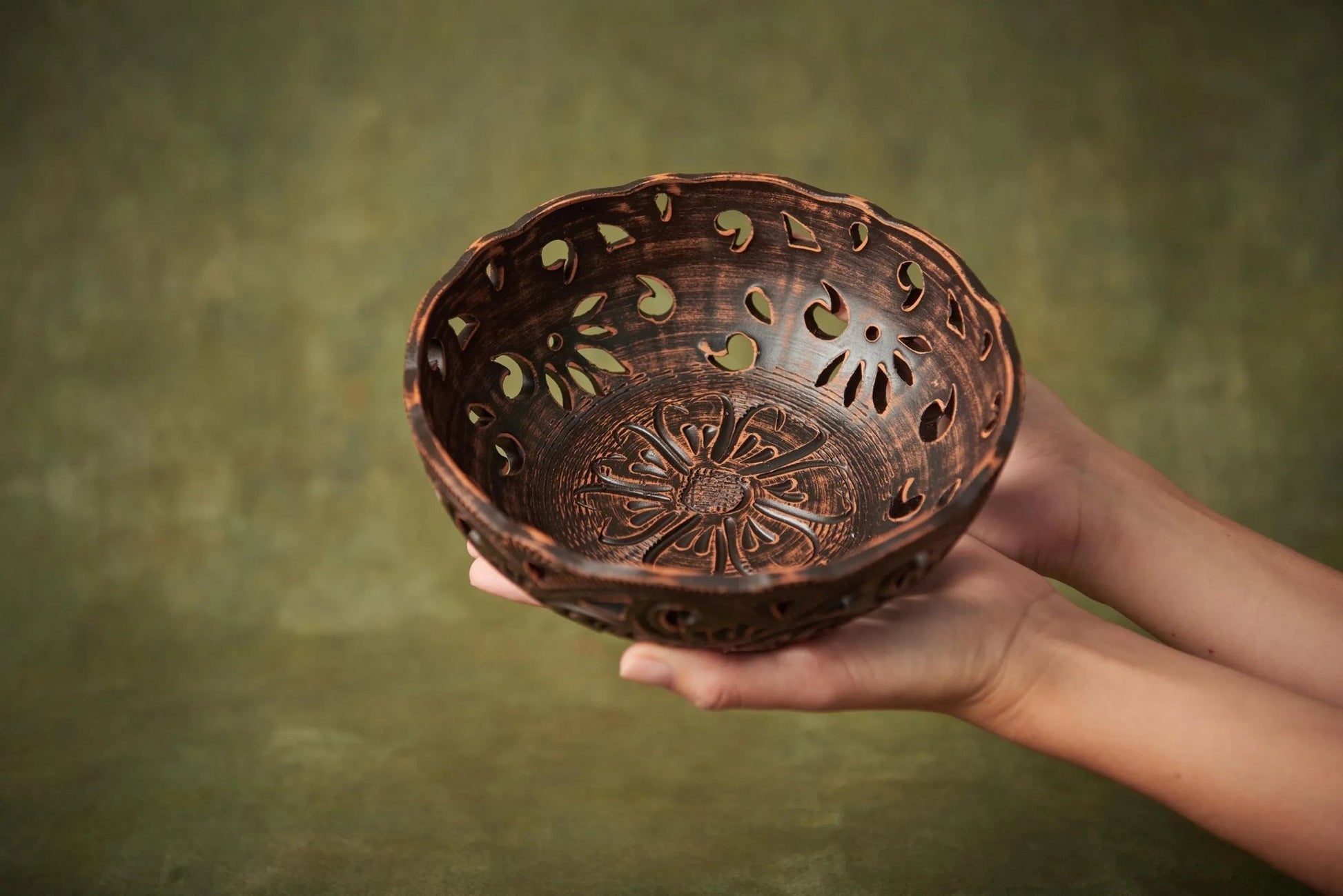 Hand holding a rustic handmade ceramic candy bowl with carved floral patterns, clayproductsshop