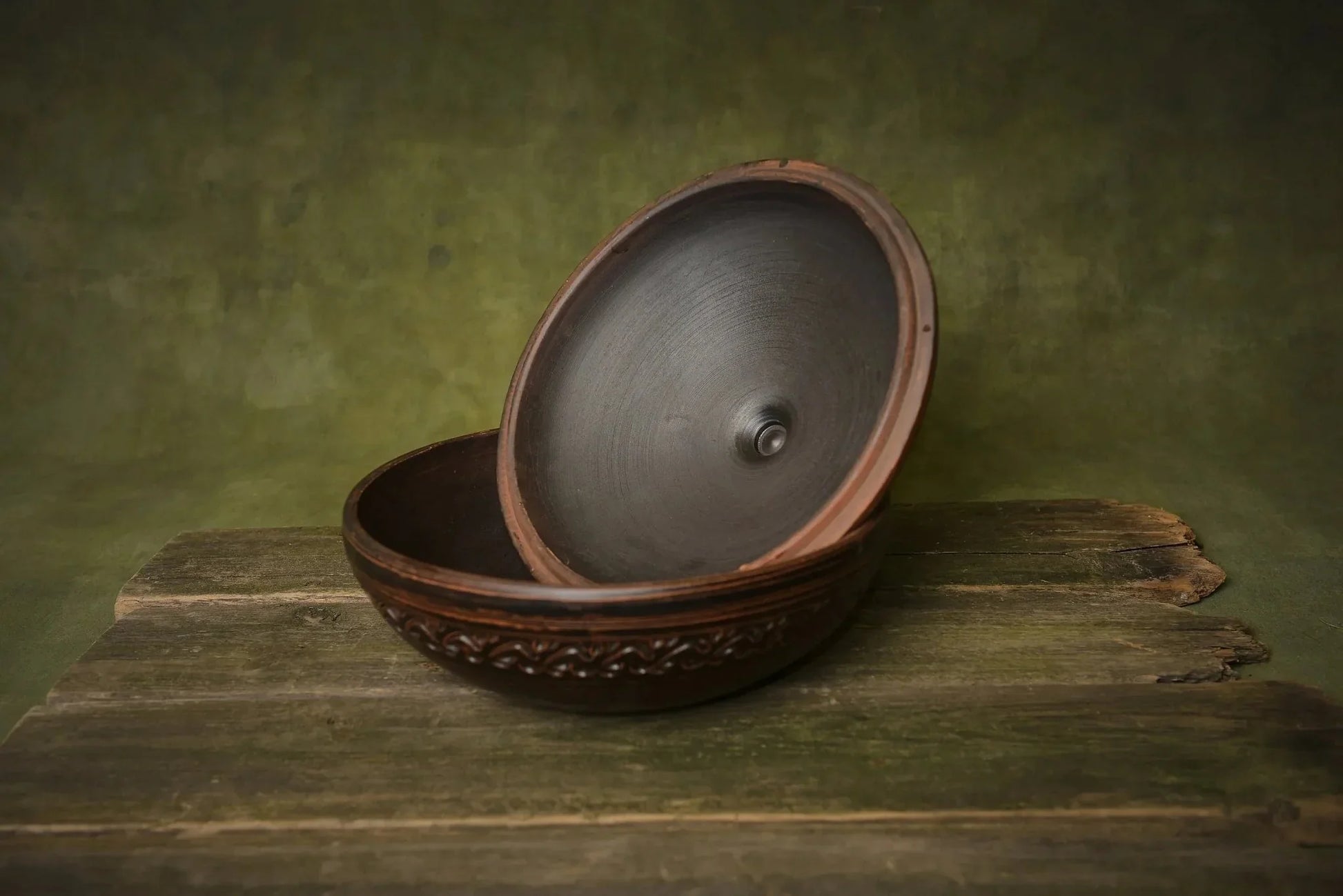 Handmade ceramic clay cooking pot with lid, round oven-safe baking dish on rustic wood