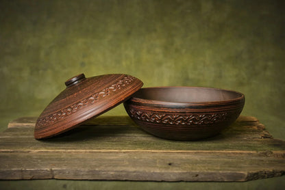 Handmade clay cooking pot with lid, rustic design, artisan kitchenware on wooden surface