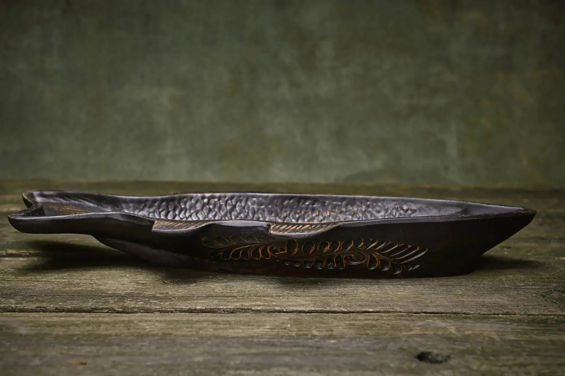 Handmade ceramic fish-shaped dish with textured details on rustic wood surface