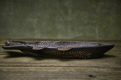 Handmade ceramic fish-shaped dish with textured details on rustic wood surface
