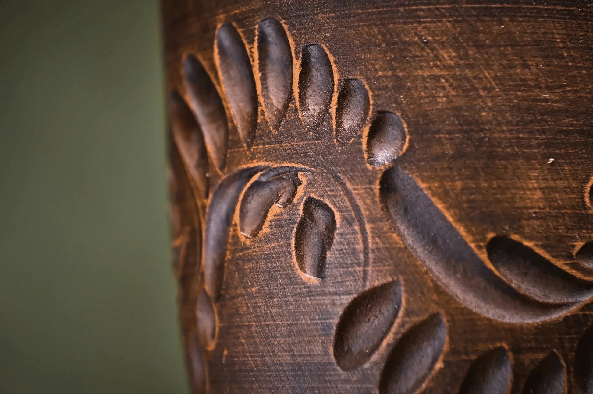 Close-up of handmade engraved clay tumbler with unique carved pattern, artisan pottery cup
