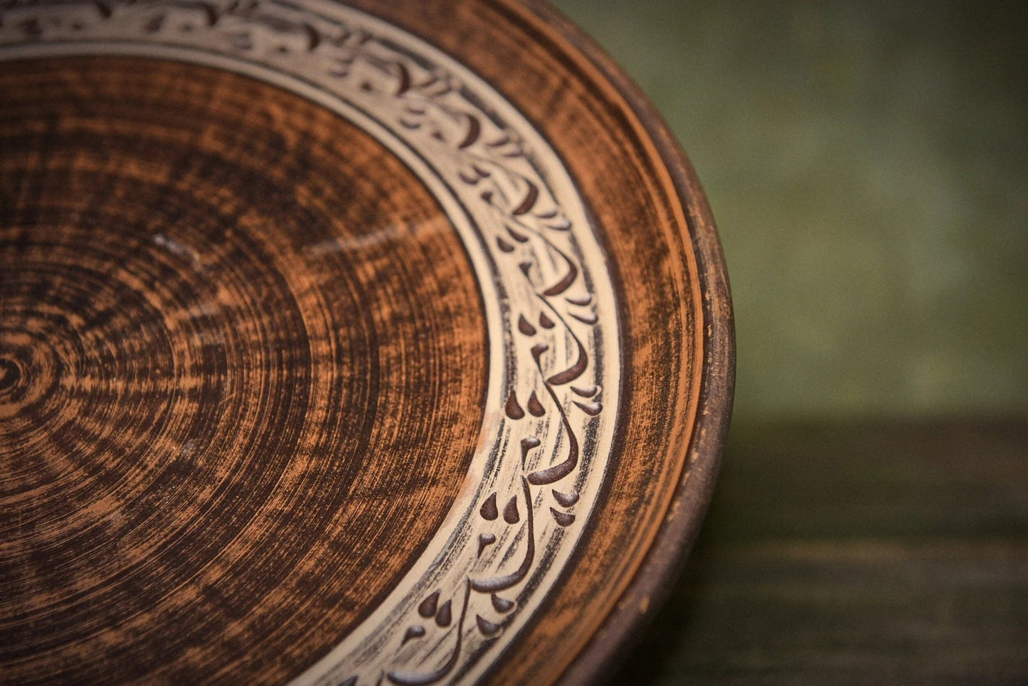 Handmade ceramic clay pizza plate with carved decorative border, rustic artisan kitchenware