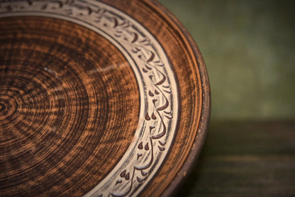 Handmade ceramic clay pizza plate with carved decorative border, rustic artisan kitchenware