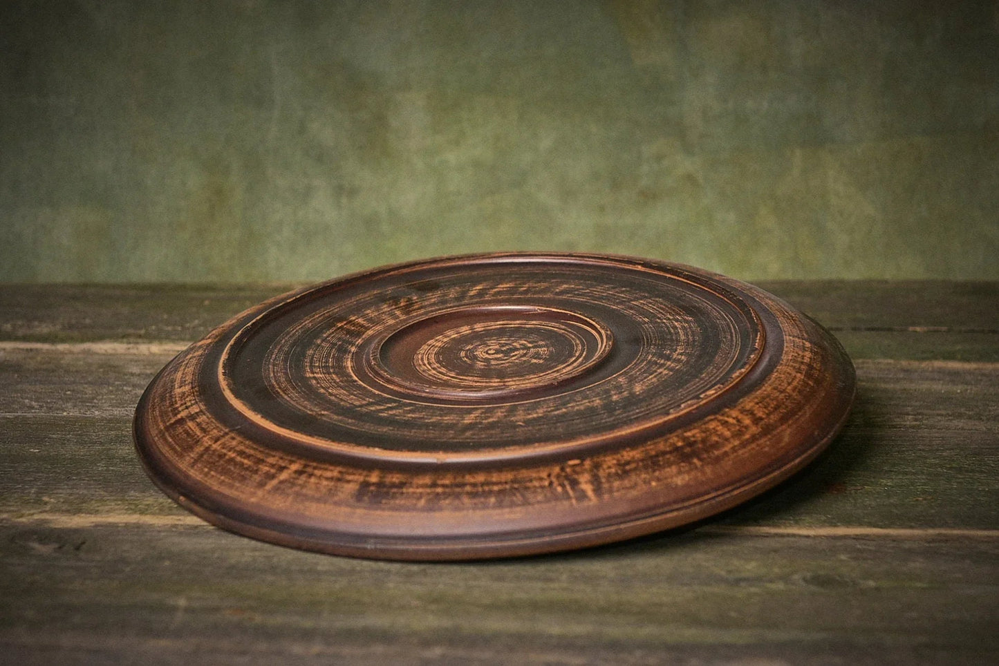 Handmade clay ceramic pizza plate with rustic finish on wooden surface