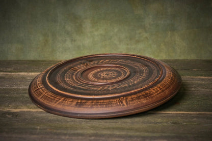 Handmade clay ceramic pizza plate with rustic finish on wooden surface