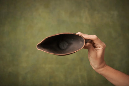 Hand holding a handmade ceramic sauceboat milk jug with rustic brown pottery finish