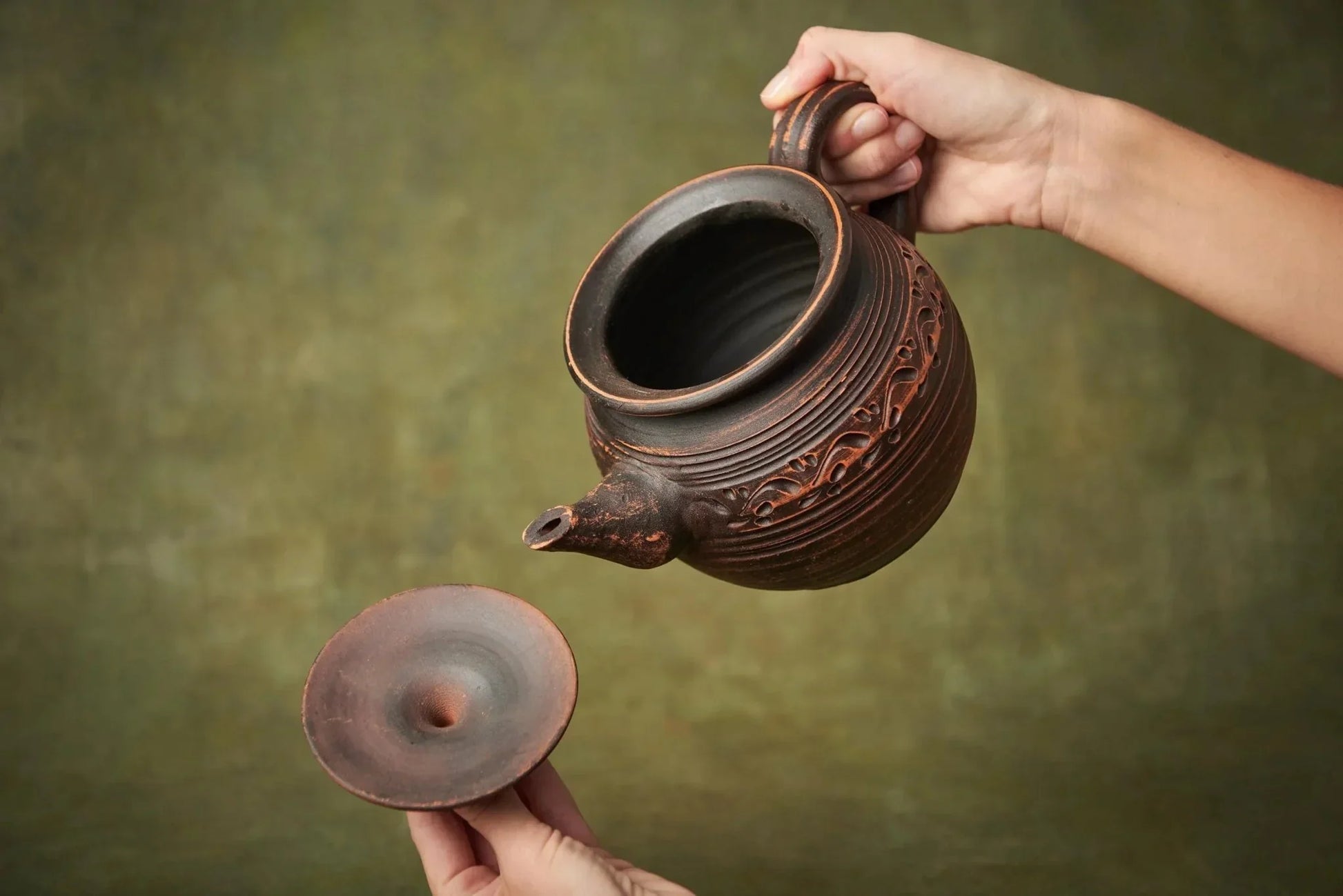 Handmade ceramic teapot with hand-engraved design, lid removed, artisan clay home decor.