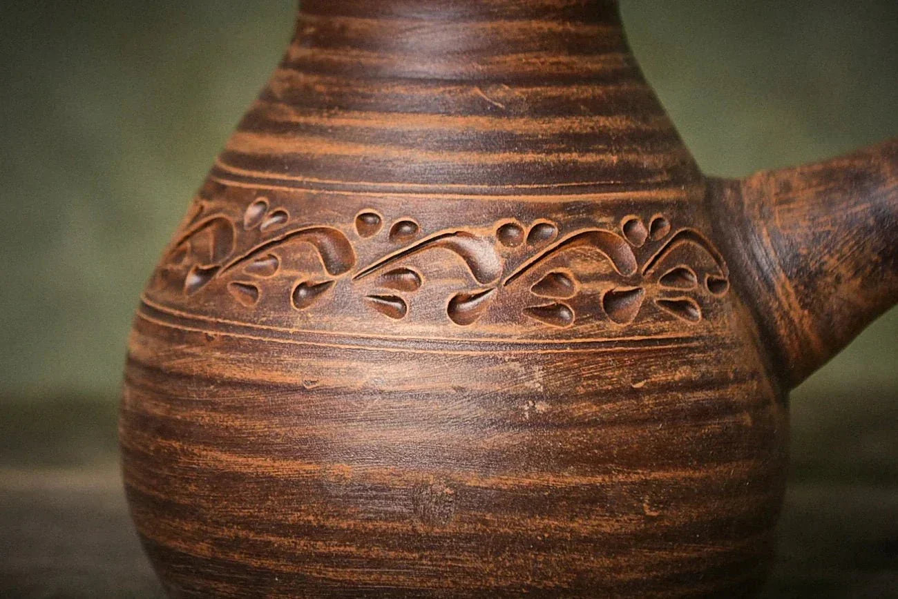 Handmade ceramic cezve coffee pot in red clay with carved floral design, artisan pottery