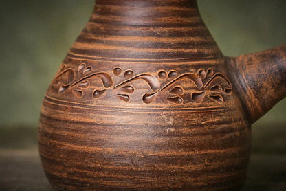 Handmade ceramic cezve coffee pot in red clay with carved floral design, artisan pottery