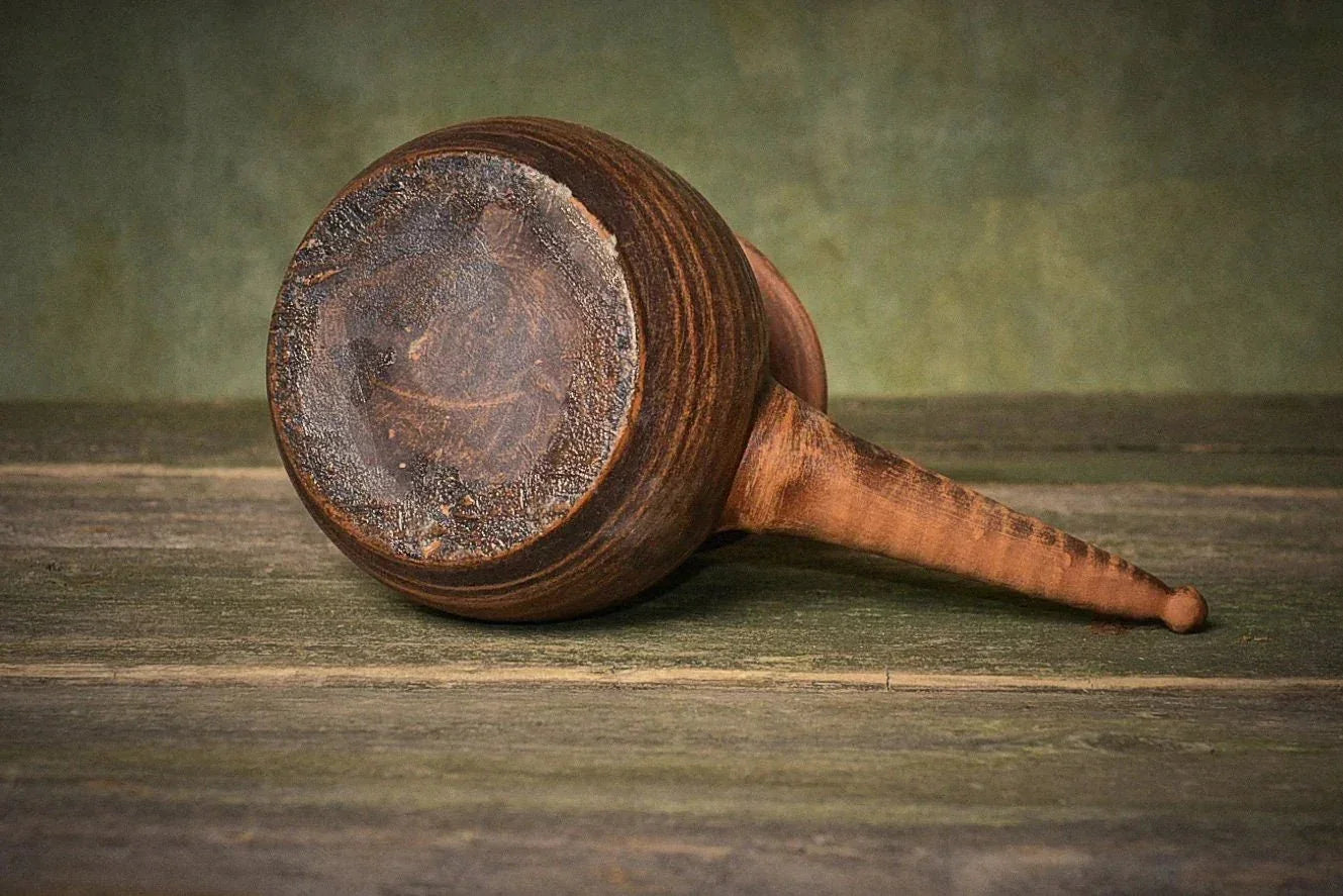 Handmade red clay Turkish coffee pot with handle on rustic wood surface