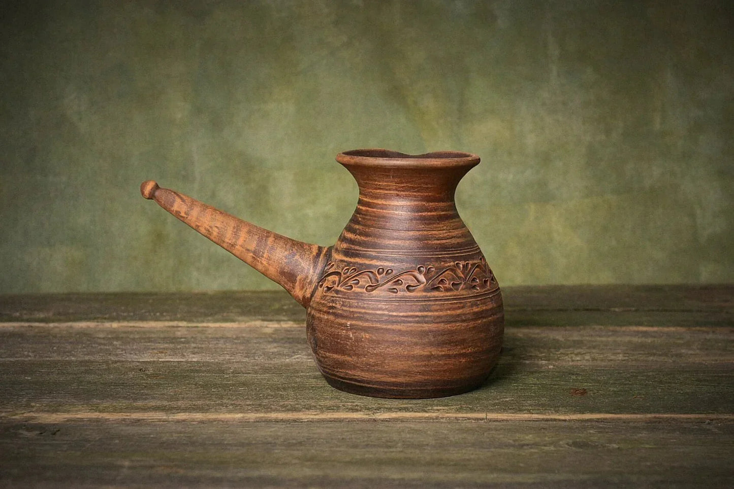Handmade ceramic cezve red clay coffee pot with handle on rustic wooden surface