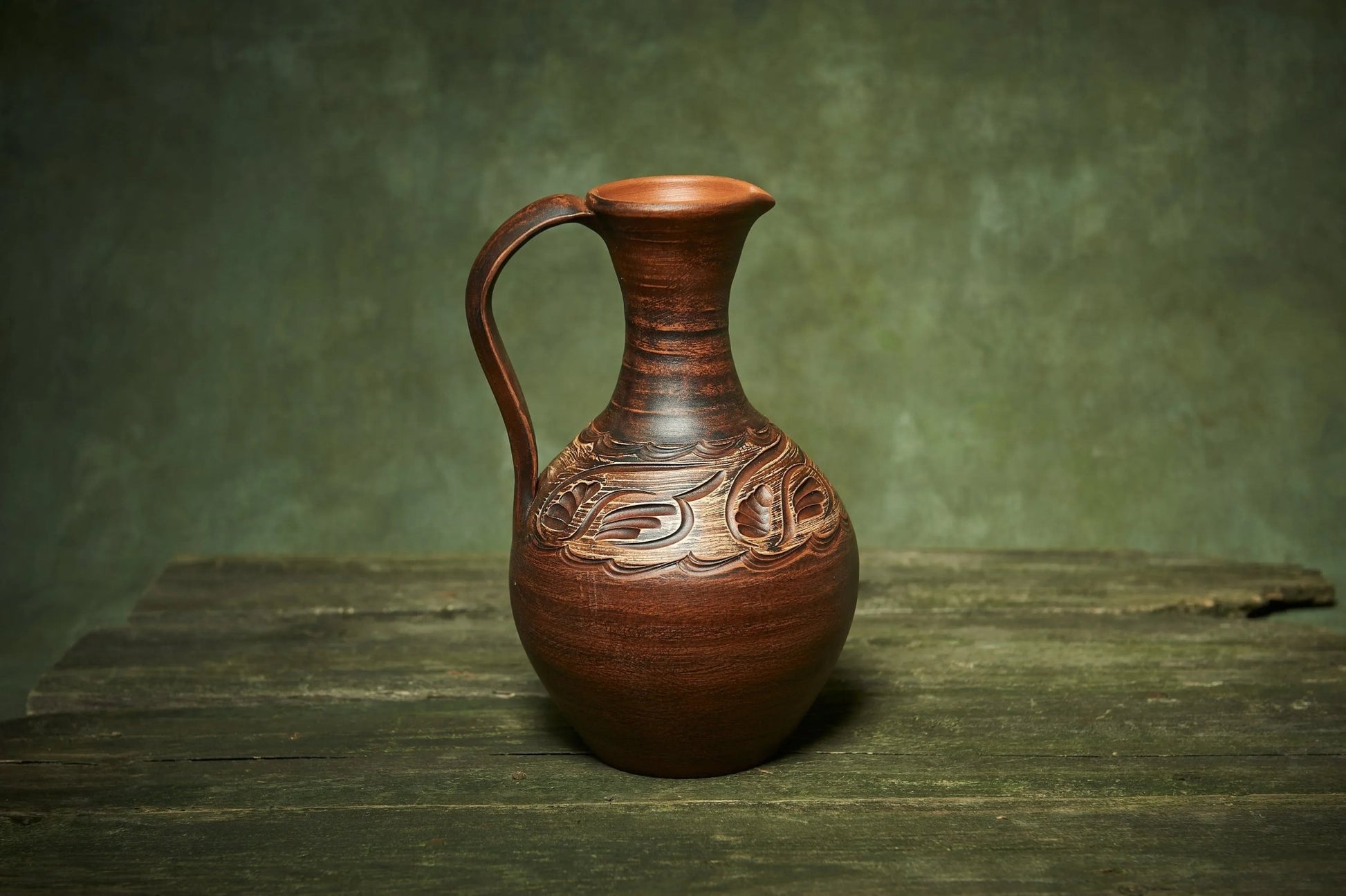Handmade ceramic pitcher with carved pattern on rustic wooden table, artisan clay homeware