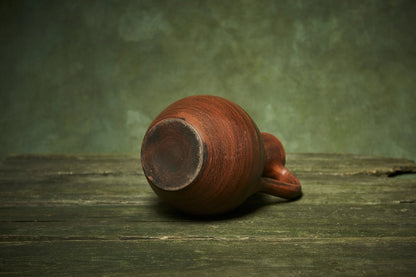 Handmade ceramic pitcher with handle on rustic wooden table, artisan-crafted homeware