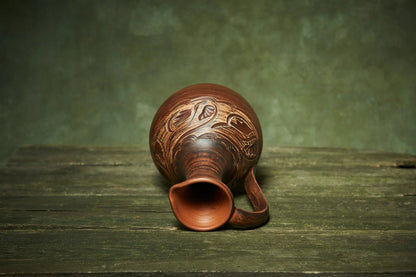 Handmade ceramic pitcher with carved patterns on rustic wood, artisan clay homeware