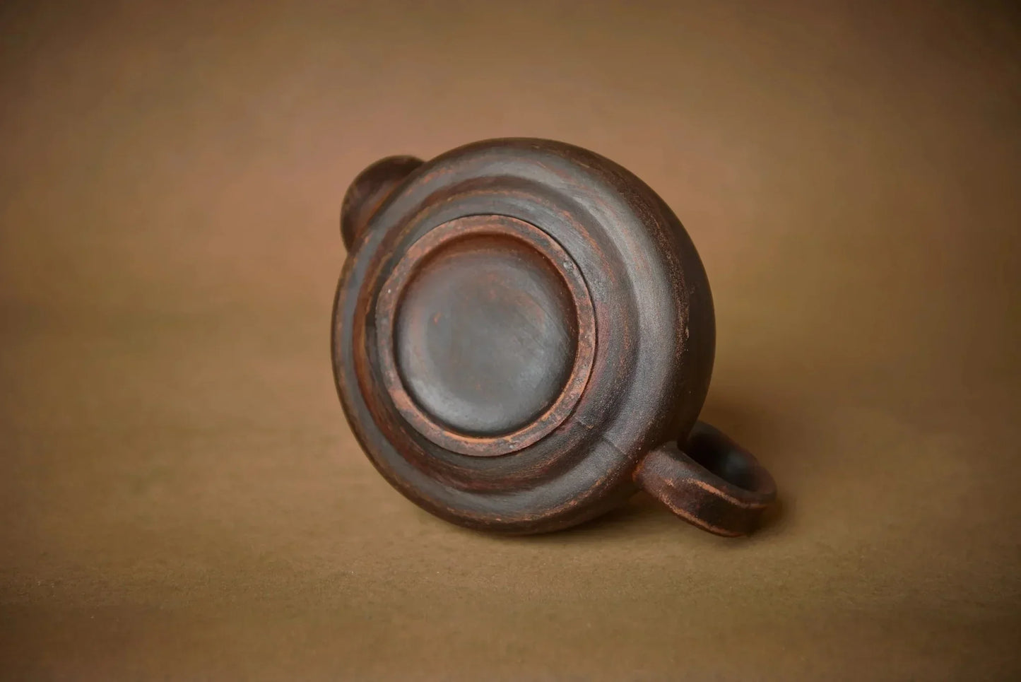 Handmade ceramic teapot base with rustic texture, artisan clay homeware on brown background