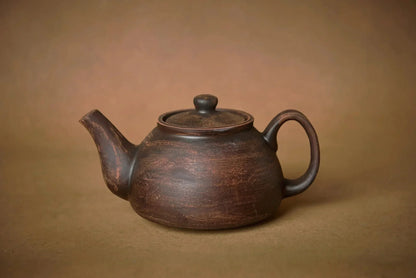 Handmade ceramic teapot, artisan pottery in rustic brown, on a neutral background