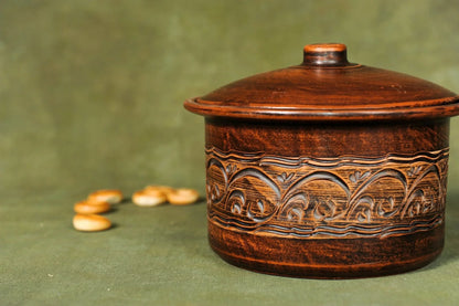Handmade clay pot casserole with intricate patterns, artisan homeware on green background