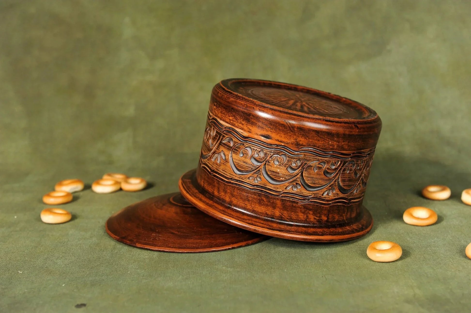 Handmade clay bread baking pan with ornate engraving on green background, artisan homeware