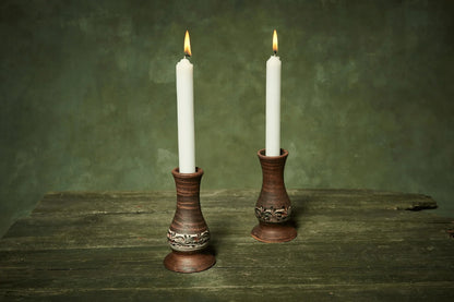 Set of two handmade ceramic candlestick holders with white candles on rustic wood table