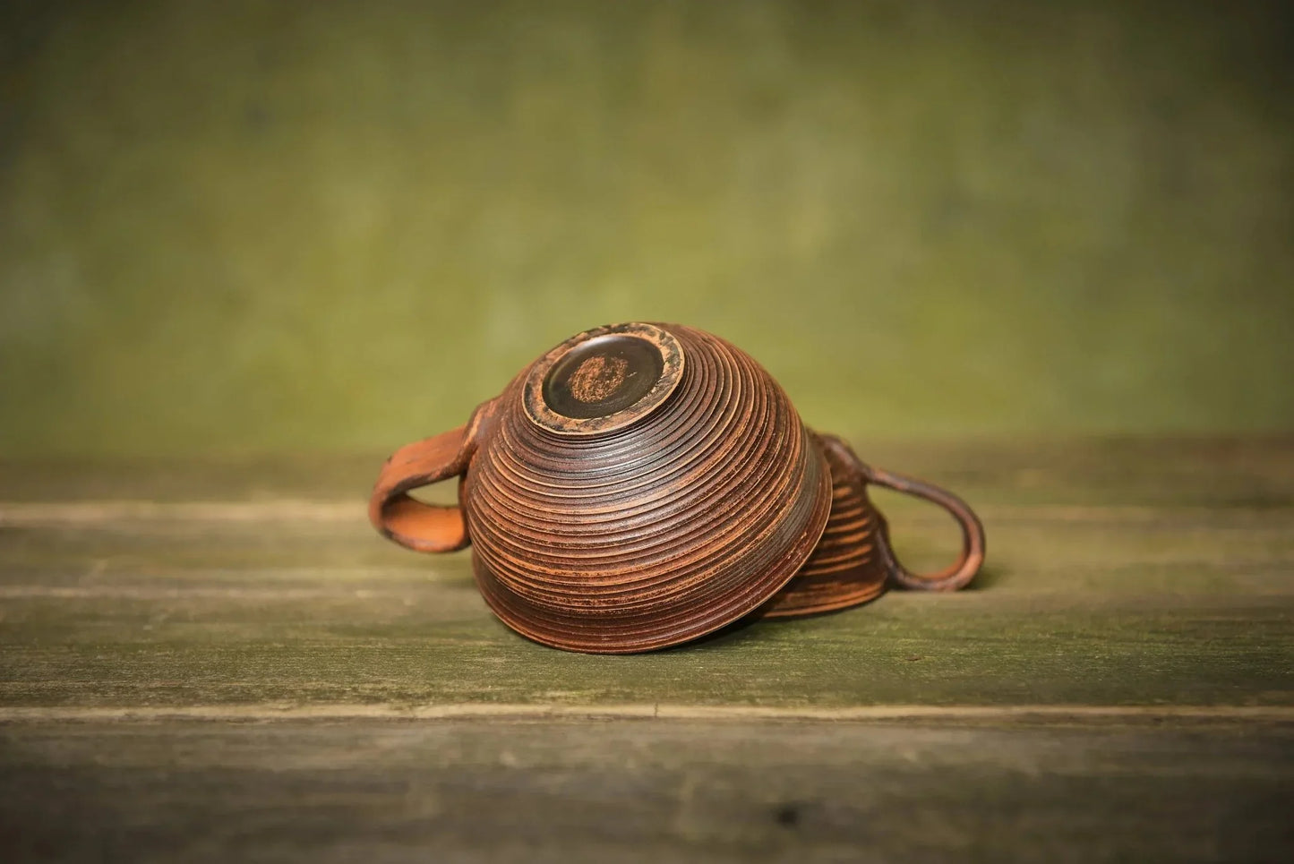 Set of two handmade ceramic clay mugs with textured brown finish on rustic wood surface