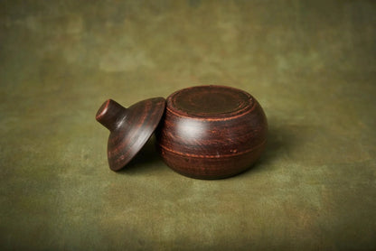 Handmade small ceramic clay baking pot with lid, rustic pottery kitchen cookware on green background