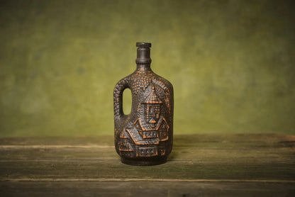 Handmade small ceramic clay bottle with cork and engraved house design on rustic wood