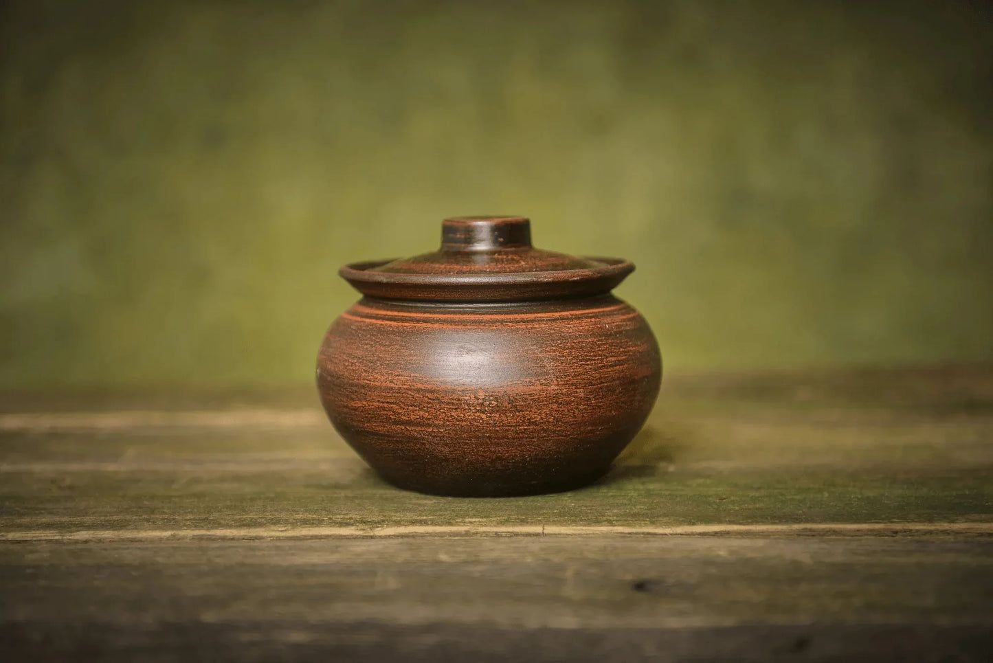 Handmade ceramic sugar bowl with lid, brown stoneware jar on rustic wood table