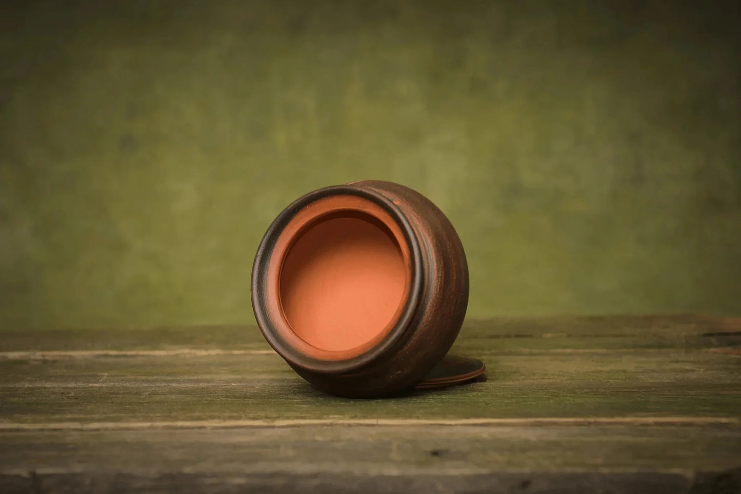 Handmade ceramic sugar bowl with lid, brown pottery storage jar on rustic wooden surface